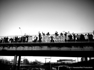 On Nov. 17, members of OccupyKC drop banners over the I-70 bridge to protest racial injustice and unemployment. Signs saying “End Racism Jobs 4 All” and “Jobs for all now” are hung over the bridge during rush hour traffic.