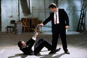 Harvey Keitel as Mr. White (standing) suspects Steve Buscemi as Mr. Pink (on the ground) of being a rat.