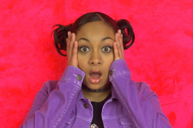 Former Disney Channel Star, Raven Symone posing in front of a pink background, mouth open wide looking shocked
