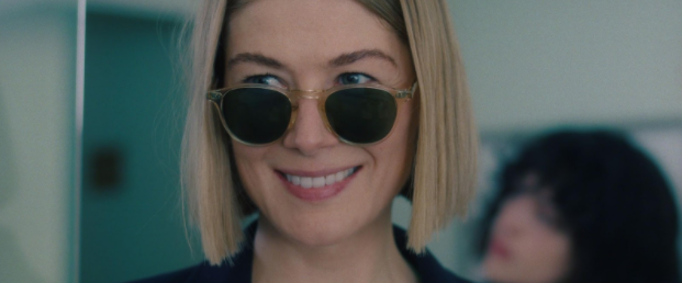 From the shoulders up view of Rosamund Pike, wearing sunglasses and smiling wide