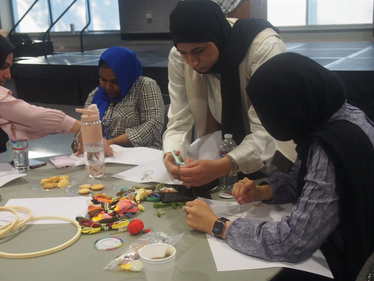 A group of attendees works on their fabric together. 