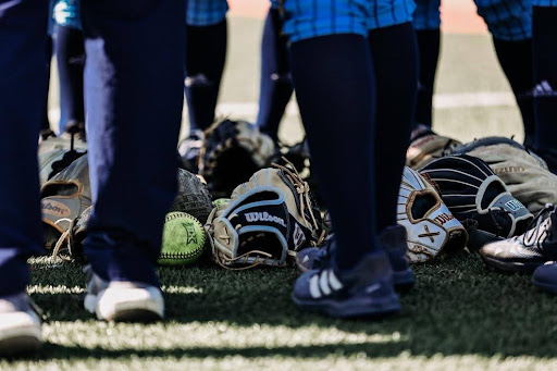 Softball team surrounding its gloves.