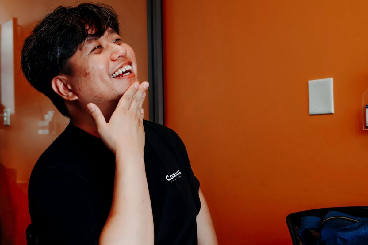 Ian Chung smiling in a room with orange walls. 