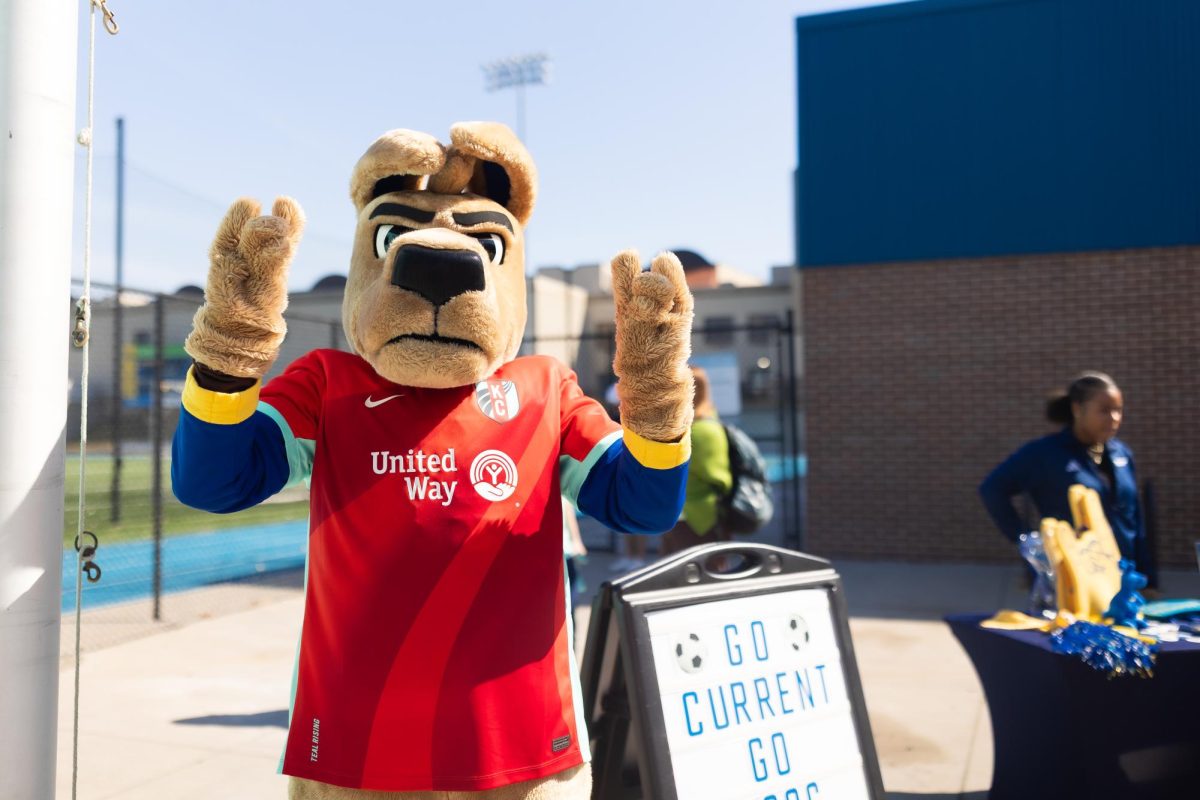 Kasey the Kangroo, UMKC's mascot, does the "roo up" hand sign at a KC Current pop-up on campus. 
