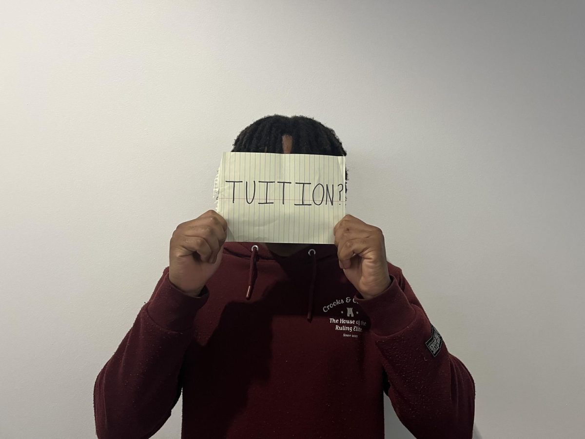 Peter Okeke, UMKC student holding a sign that says "TUITION?"