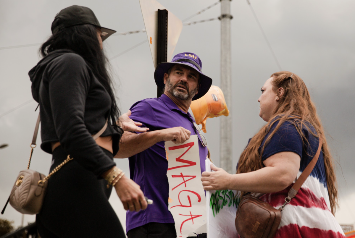 Two participants at the No Kings 2.0 rally confront a pro-Trump bystander with a ripped sign reading ‘MAGA.’
