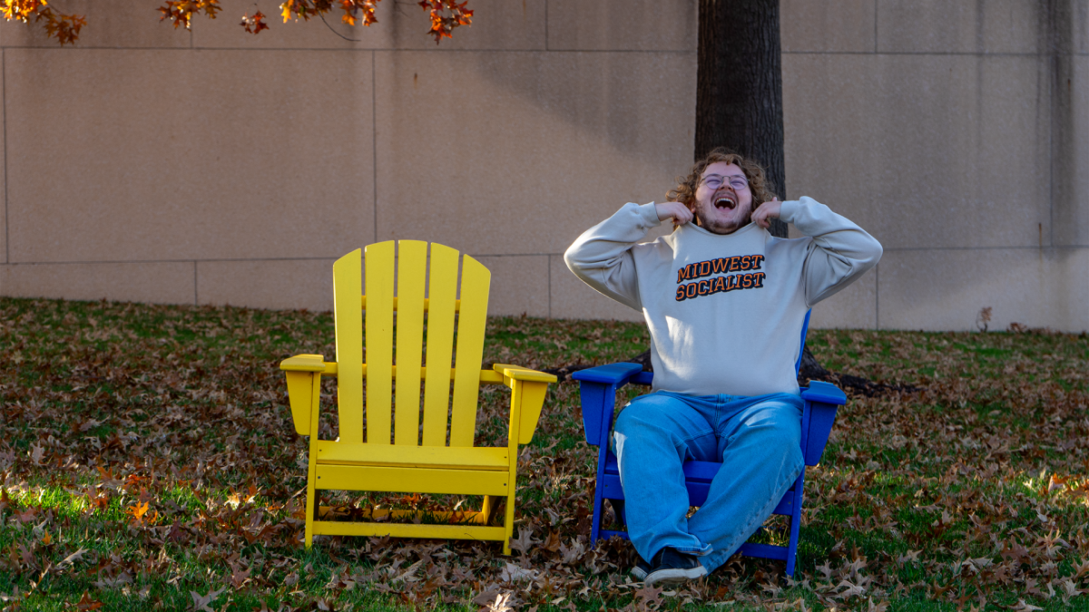 YDSA President Samuel Lamar sitting outside of Swinney Recreation Center excited for Mamdani's win, wearing his "Midwest Socialist" graphic shirt.
