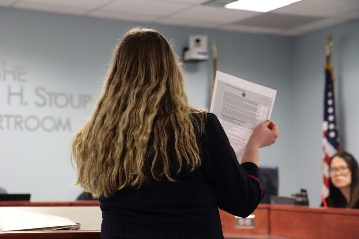 Co-petitioner Morgen Foster presenting her case to the court, holding a copy of a paper related to the case.